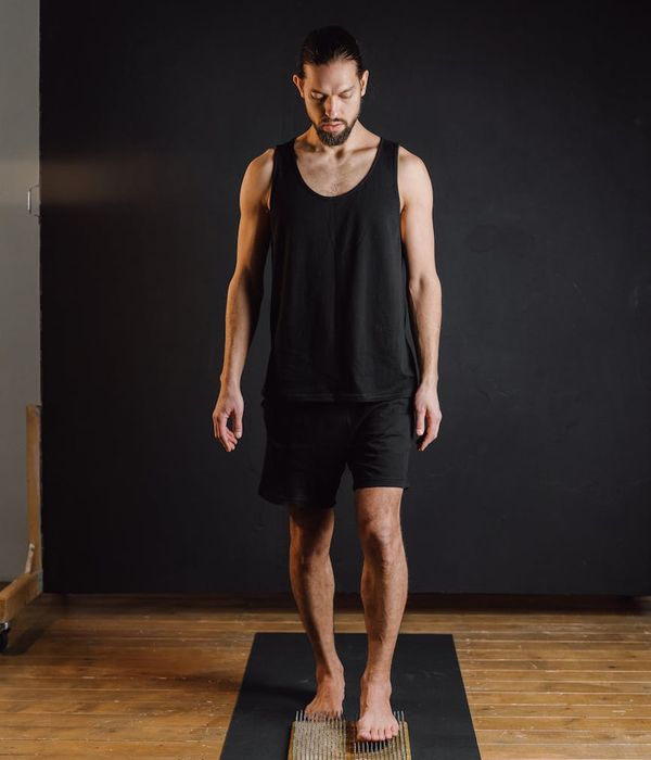 Person sitting in a calm meditation pose against a sand-colored background.